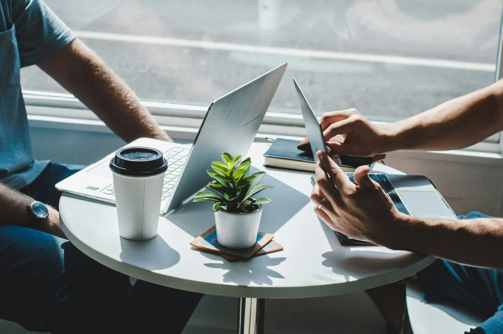 Två personer sitter mitt emot varandra med laptops och kaffe under ett affärsmöte